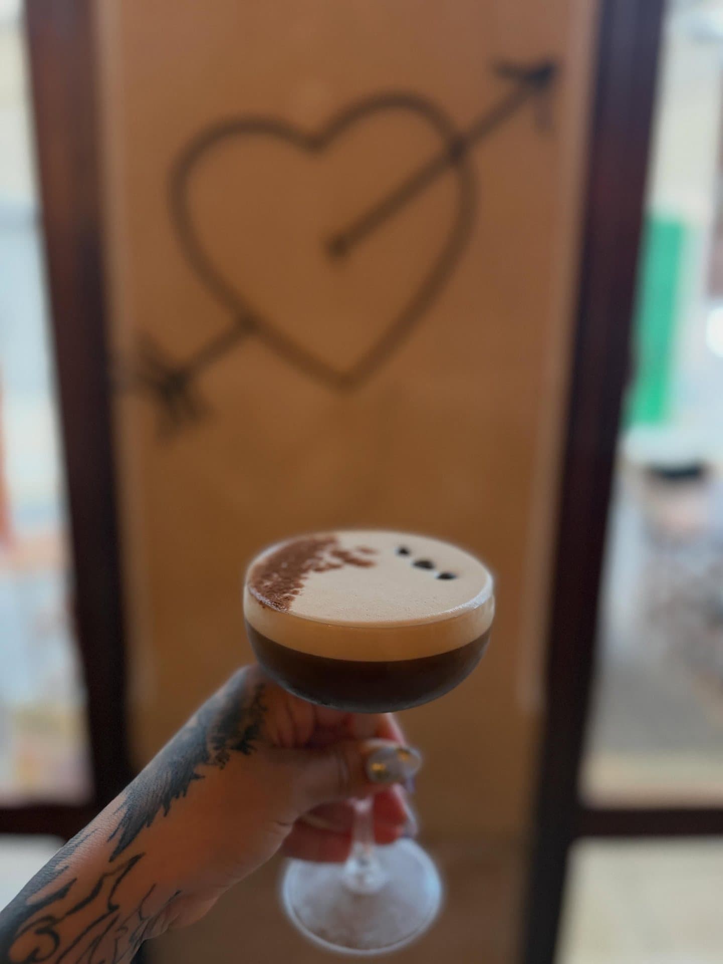 Un espresso martini junto a una puerta con un corazón dibujado