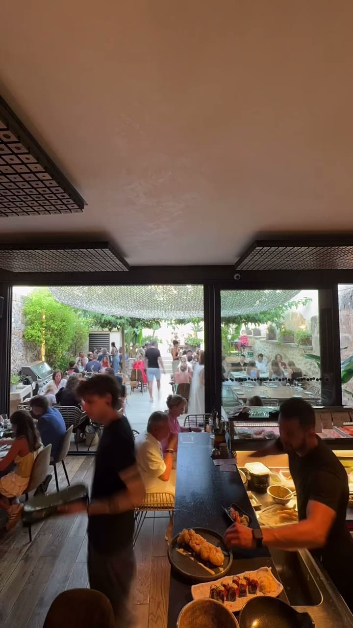 Barra de sushi con el patio lleno al fondo