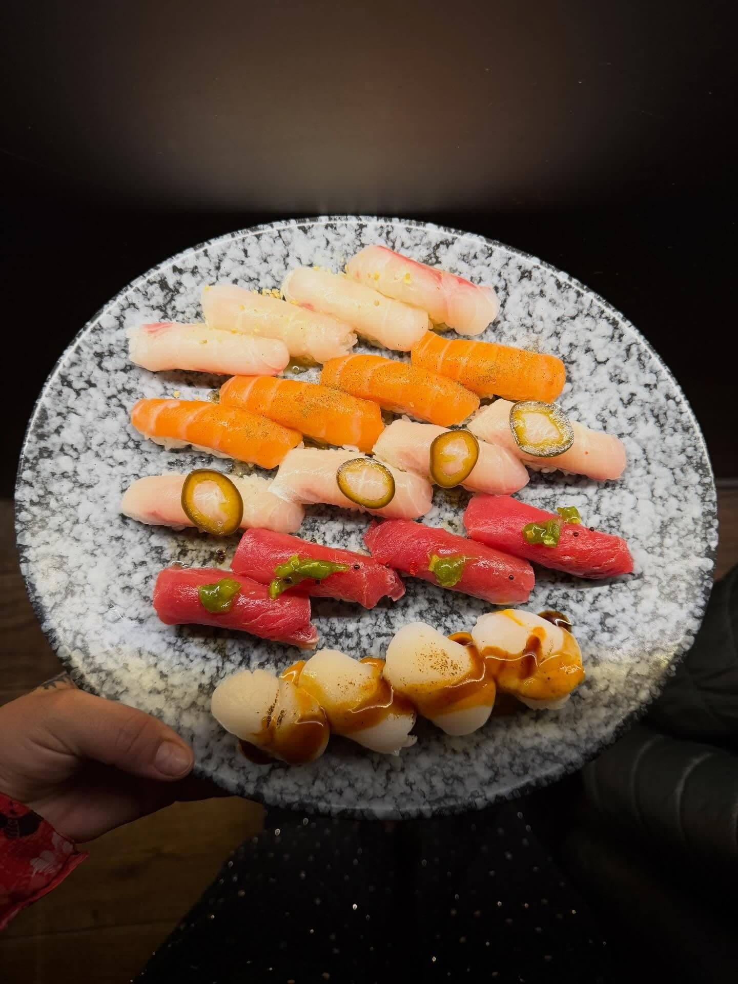 Un plato de piedra con nigiris variados, sostenido en la mesa